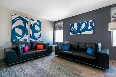 a living room with two black leather couches and colorful pillows at Aloft Newport on the Levee in Newport