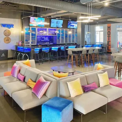 a couch with colorful pillows in a room with a bar at Aloft Newport on the Levee in Newport