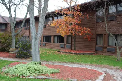 a house with a tree in front of it at Carlton Lodge Hotel and Suites in Adrian