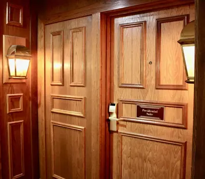 a wooden door in a room with a sign on it at Carlton Lodge Hotel and Suites in Adrian