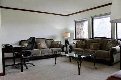 a living room with two couches and a table at Carlton Lodge Hotel and Suites in Adrian