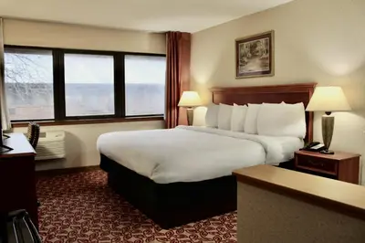 a hotel room with a large bed and windows at Carlton Lodge Hotel and Suites in Adrian