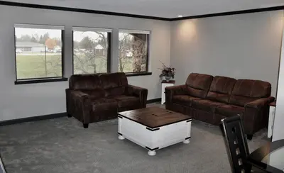 a living room with two couches and a coffee table at Carlton Lodge Hotel and Suites in Adrian