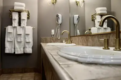 a bathroom with a sink and a mirror and towels at Carlton Lodge Hotel and Suites in Adrian