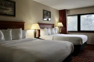 a hotel room with two beds and a window at Carlton Lodge Hotel and Suites in Adrian