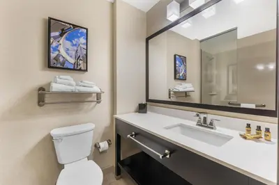 a bathroom with a sink and a toilet and a mirror at Best Western Plus Franciscan Square Inn & Suites Steubenville in Steubenville