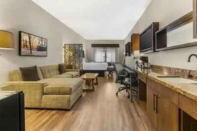 a living room with a couch and a desk at Best Western Plus Franciscan Square Inn & Suites Steubenville in Steubenville