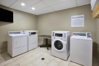 a laundry room with three washing machines and a table at Holiday Inn Express & Suites - Parkersburg East by IHG in Parish-Morris Subdivision