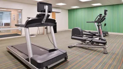 a gym with two exercise bikes and a treadmill at Holiday Inn Express & Suites - Parkersburg East by IHG in Parish-Morris Subdivision