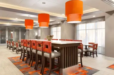 a dining room with orange chairs and a large table at Hampton Inn By Hilton North Olmsted Cleveland Airport in North Olmsted