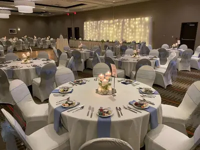 a banquet hall with white tables and white chairs at Hilton Garden Inn Findlay in Findlay