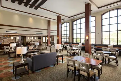 a hotel lobby with tables and chairs and windows at Staybridge Suites - Columbus Polaris by IHG in Flint