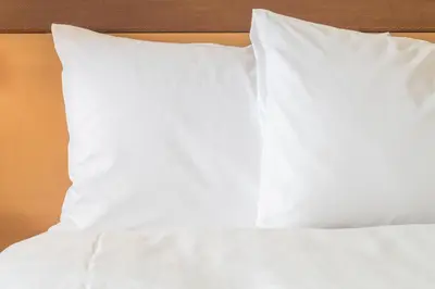 a bed with white sheets and pillows on it at Staybridge Suites - Columbus Polaris by IHG in Flint