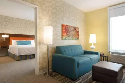 a hotel room with a blue chair and a bed at Home2 Suites By Hilton Middleburg Heights Cleveland in Middleburg Heights