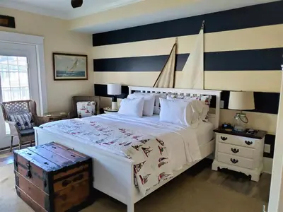 a bedroom with a large white bed with a striped wall at Anchor Inn Boutique Hotel in Put-in-Bay