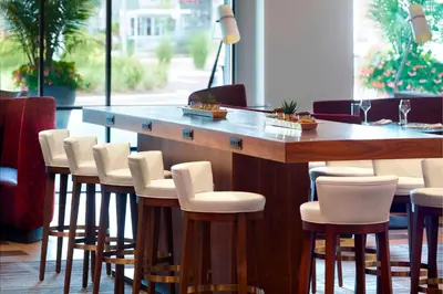 a bar with white chairs and a wooden table at Marriott Columbus OSU in Columbus
