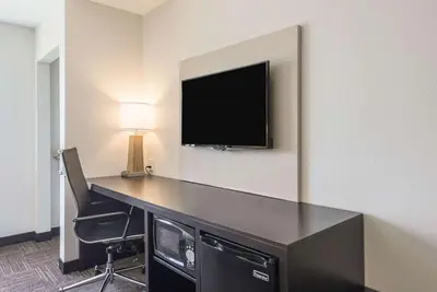 a room with a desk with a tv on a wall at Sleep Inn & Suites Galion in Galion