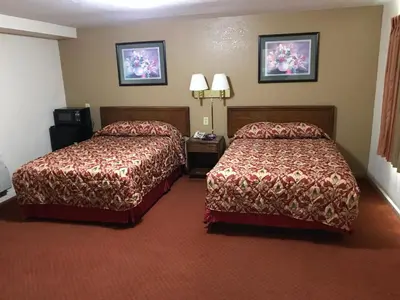 a hotel room with two beds and two lamps at Travelers Inn in New Martinsville