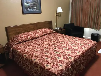 a bed in a hotel room with a red bedspread at Travelers Inn in New Martinsville