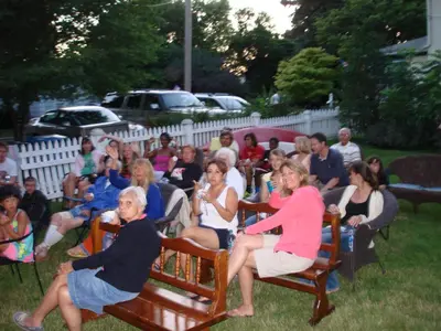a crowd of people sitting in chairs in a yard at Aunt Jane's Victorian Manor in Put-in-Bay