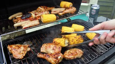 a person is cooking meat and corn on the grill at Aunt Jane's Victorian Manor in Put-in-Bay
