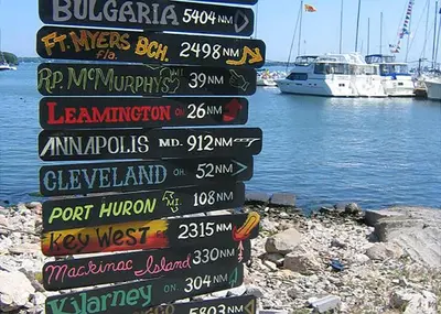 a sign with many different signs on the side of the water at Aunt Jane's Victorian Manor in Put-in-Bay