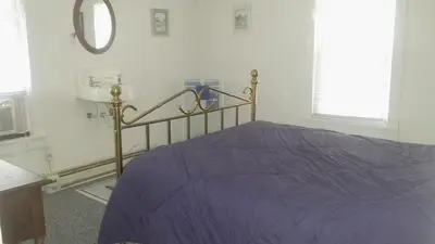a bedroom with a bed with purple sheets and a mirror at Aunt Jane's Yellow House in Put-in-Bay