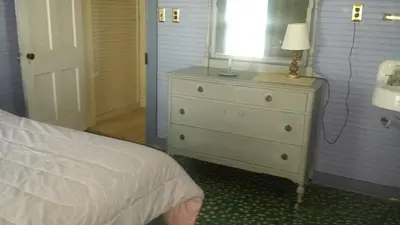 a bedroom with a bed and a dresser with a lamp at Aunt Jane's Yellow House in Put-in-Bay