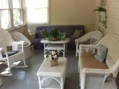 a living room with white wicker chairs and a couch at Aunt Jane's Yellow House in Put-in-Bay