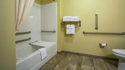 a bathroom with a tub and a toilet and towels at Cobblestone Hotel & Suites - Orrville in Orrville