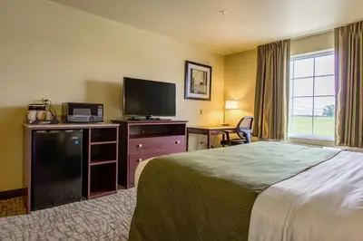 a hotel room with a bed and a flat screen tv at Cobblestone Hotel & Suites - Orrville in Orrville