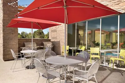 a patio with tables and chairs with red umbrellas at Home2 Suites By Hilton Columbus Dublin in Dublin