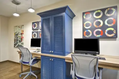 a blue cabinet with two monitors and two chairs at Home2 Suites By Hilton Maumee Toledo in Maumee