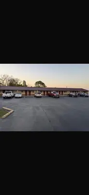 a parking lot with cars parked in front of a building at Deluxe Inn in Hebron