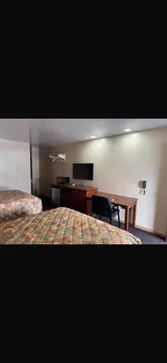 a hotel room with two beds and a desk at Deluxe Inn in Hebron