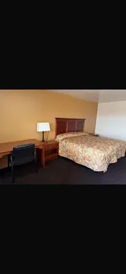 a bedroom with a bed and a desk with a lamp at Deluxe Inn in Hebron