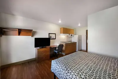 a small room with a bed and a desk and a kitchen at WoodSpring Suites Columbus Southeast in Groveport
