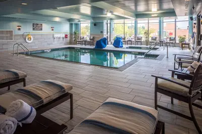 a swimming pool in a hotel lobby with chairs at Hilton Garden Inn Pittsburgh Airport in Moon Township
