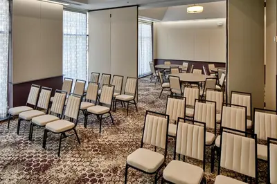 a room with chairs and tables in a room with windows at Hotel Indigo Cleveland Downtown by IHG in Cleveland