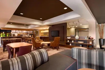 a hotel room with a couch and tables and chairs at Courtyard Akron Fairlawn in Montrose