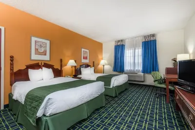 a hotel room with two beds and a flat screen tv at Baymont by Wyndham Greensburg in Greensburg