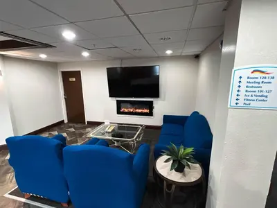 a waiting room with blue chairs and a flat screen tv at Baymont by Wyndham Greensburg in Greensburg