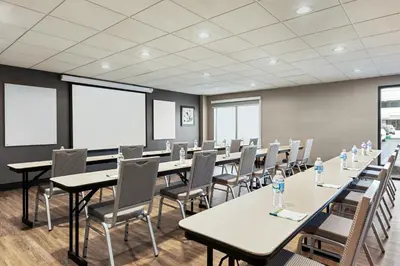 a conference room with tables and chairs and windows at Wingate by Wyndham Cincinnati Blue Ash in Blue Ash