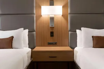 a hotel room with two beds and a nightstand between them at Wingate by Wyndham Cincinnati Blue Ash in Blue Ash