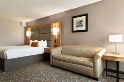 a hotel room with a bed and a chair at Wingate by Wyndham Cincinnati Blue Ash in Blue Ash
