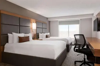 a hotel room with two beds and a desk at Wingate by Wyndham Cincinnati Blue Ash in Blue Ash