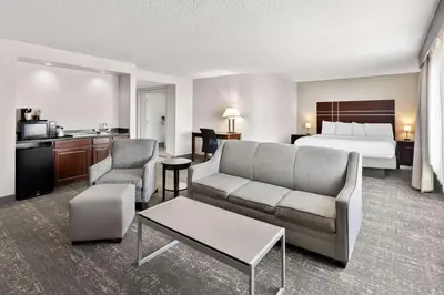 a hotel room with a bed and a living room at Best Western Luxbury Inn Fort Wayne in Fort Wayne
