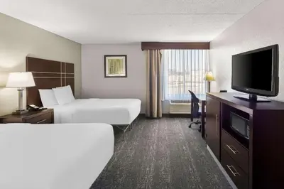 a hotel room with two beds and a flat screen tv at Best Western Luxbury Inn Fort Wayne in Fort Wayne