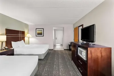 a hotel room with two beds and a flat screen tv at Best Western Luxbury Inn Fort Wayne in Fort Wayne