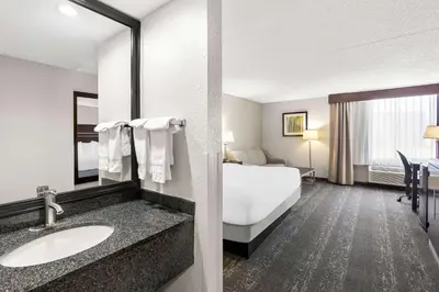 a hotel room with a bed and a bathroom at Best Western Luxbury Inn Fort Wayne in Fort Wayne